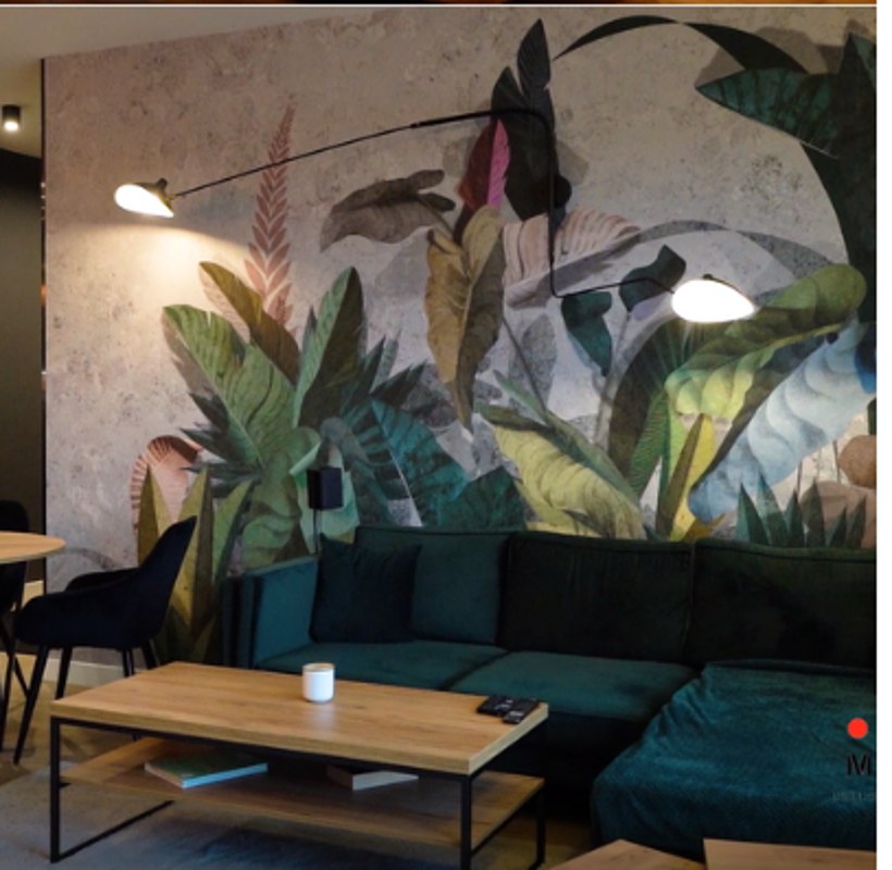 Salon z tapetą roślinną i zieloną sofą